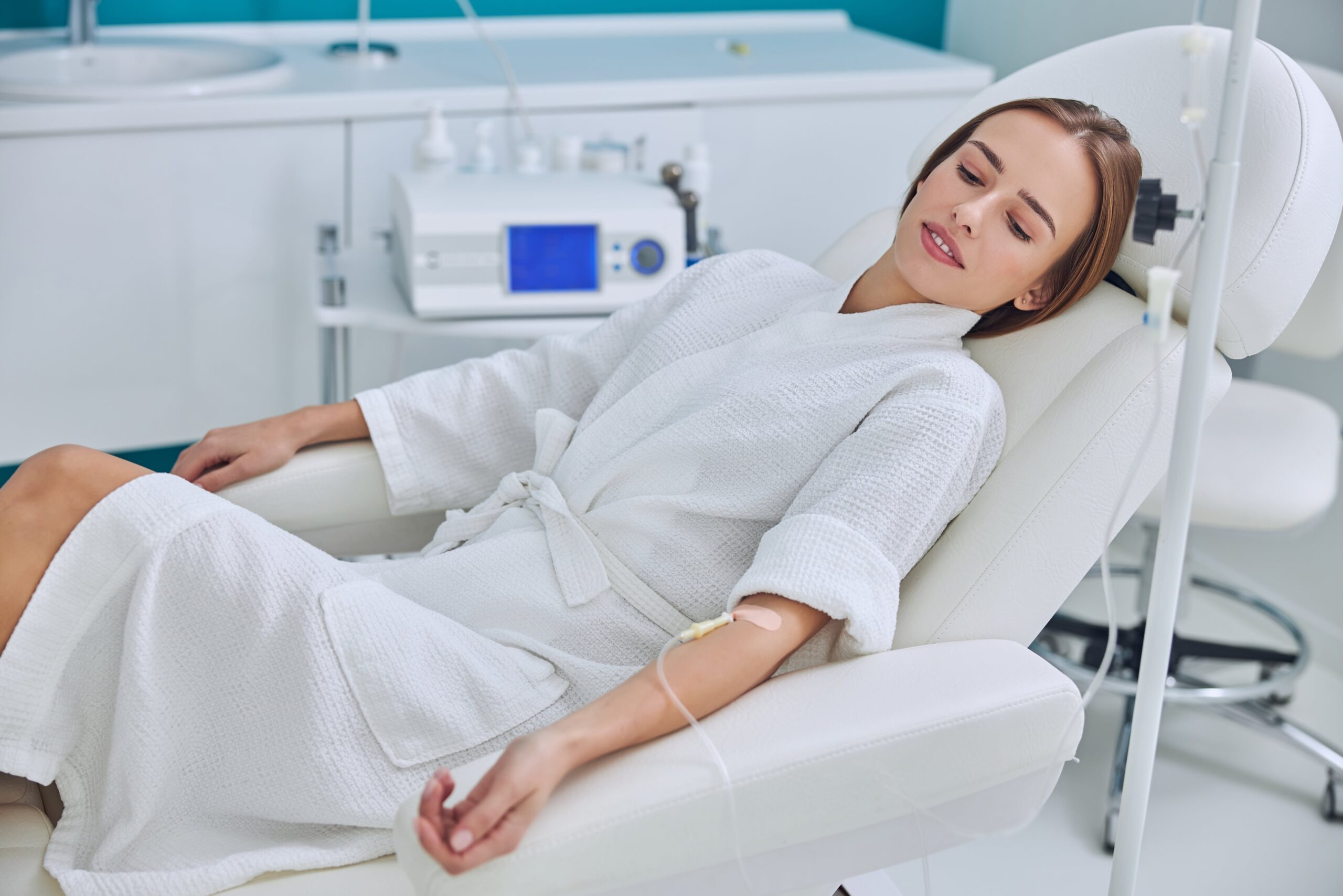 A relaxed woman receiving a vitamin drip in a clinical setting.