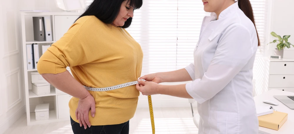 Doctor measuring patient’s waist during a medical weight loss consultation.