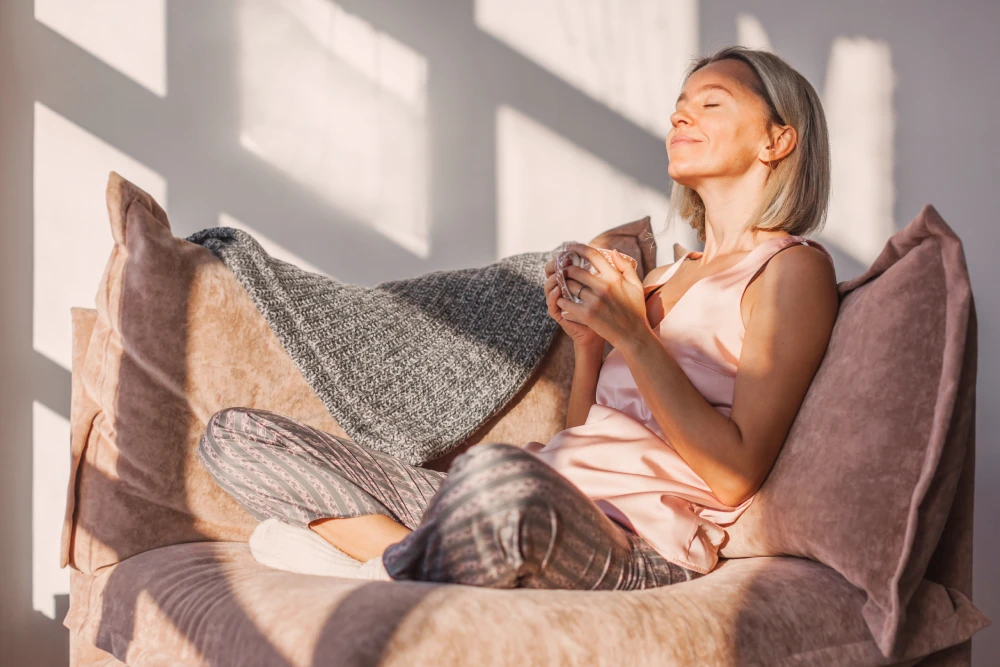 A relaxed woman enjoys a peaceful moment on the couch after hormone therapy.