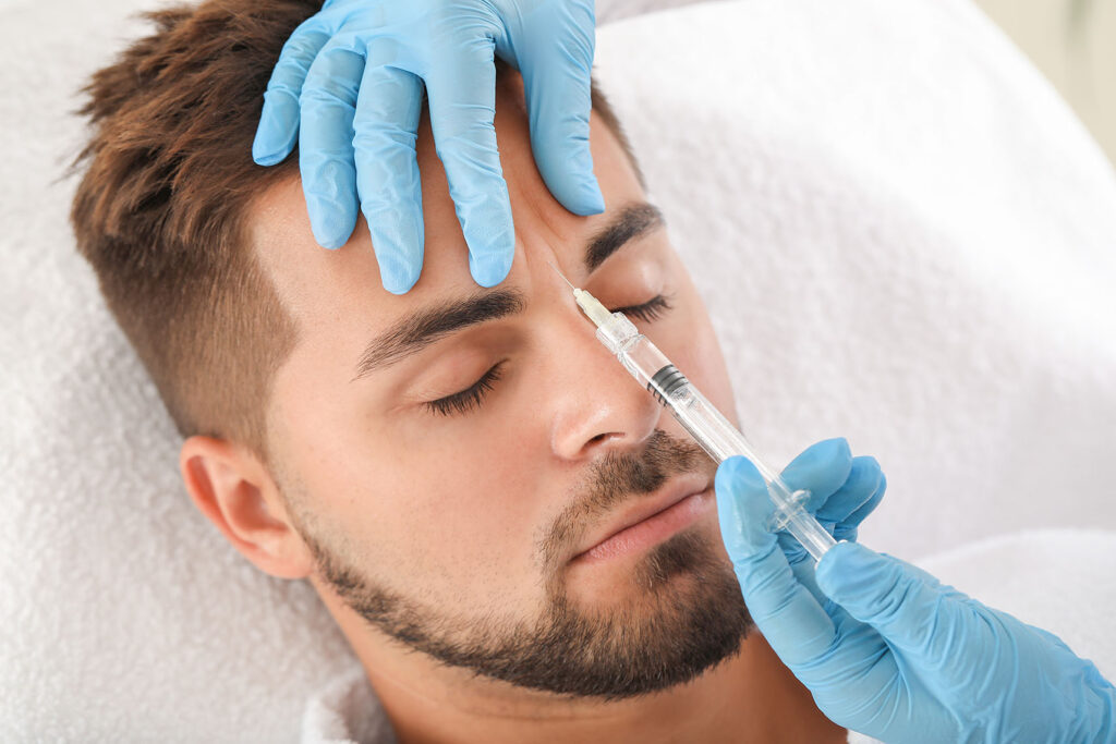 Medical professional administering a forehead injection to a male patient
