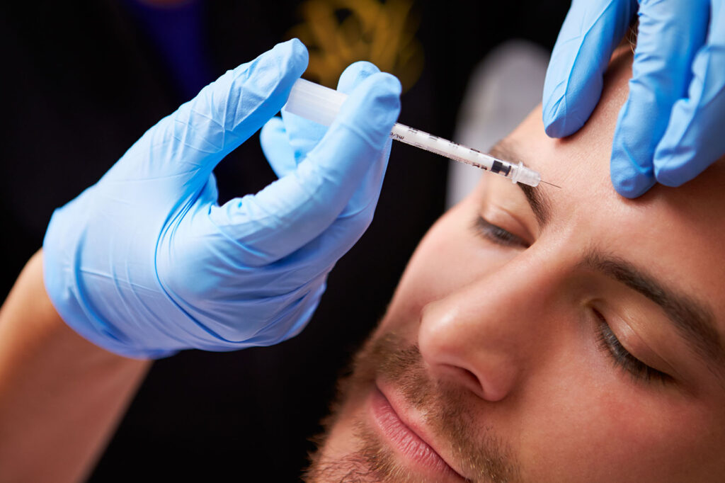 Medical professional administering an injection between a male patient’s eyebrows